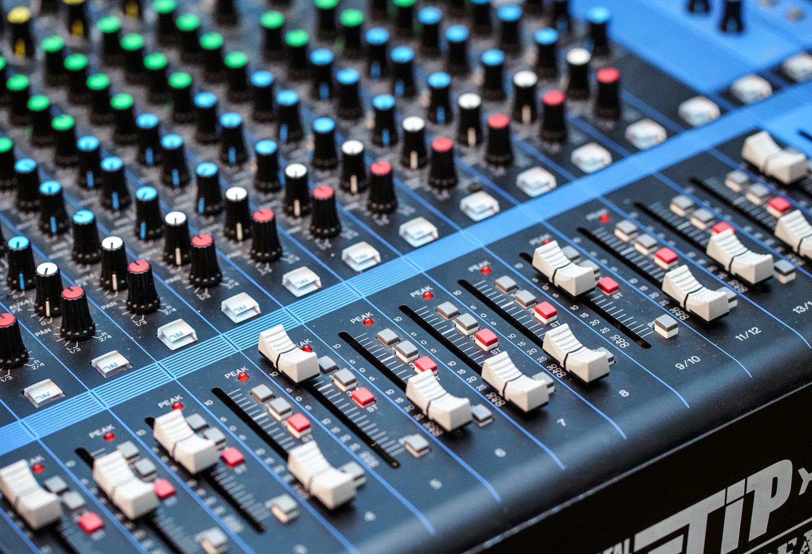 Close-up of an audio mixing console packed with rows of colored knobs and faders, the kind of hands-on control surface a custom visualizer settings panel is the software version of