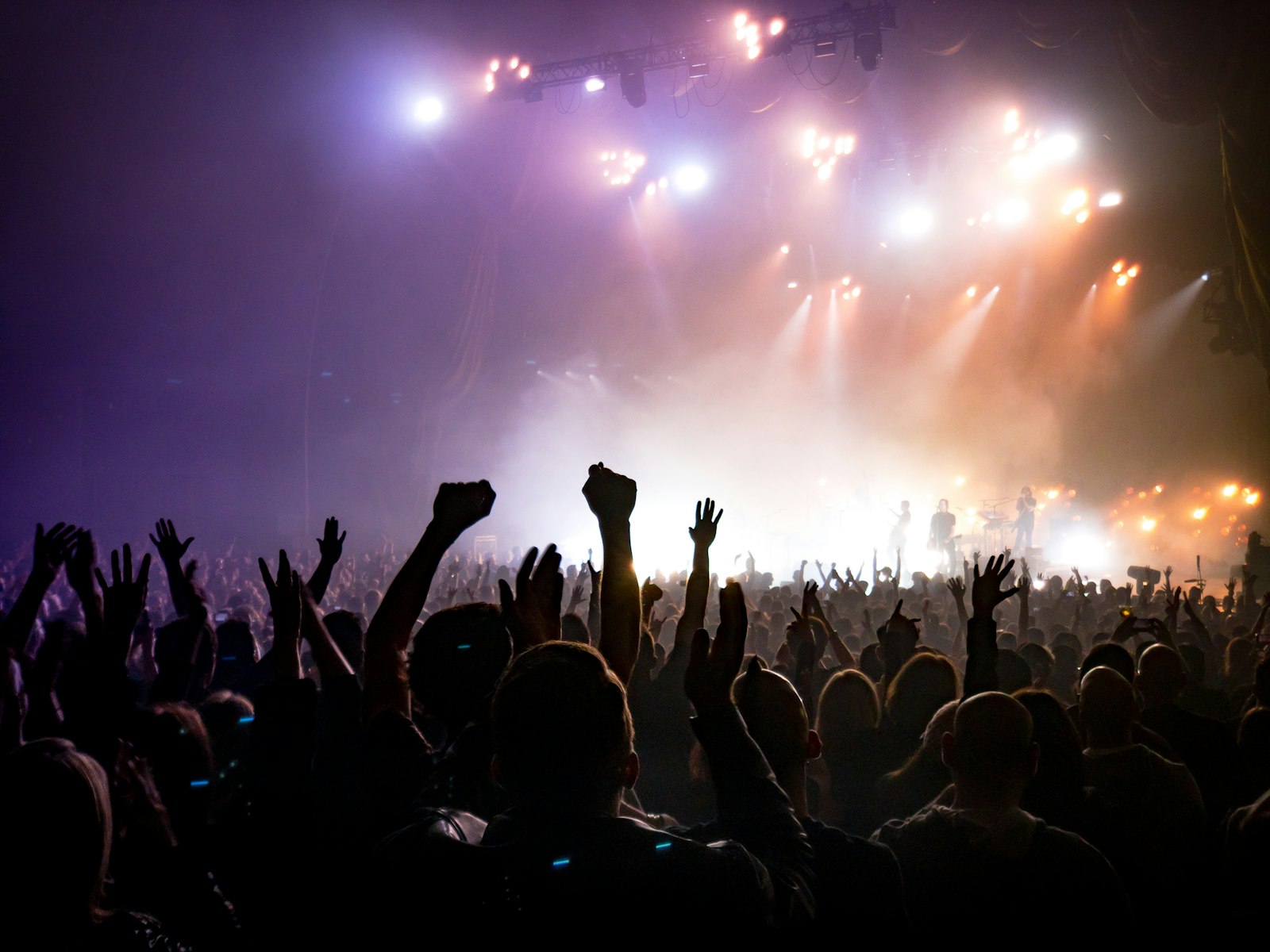 A dark club crowd with hands raised facing a wall of bright stage lights and haze, the kind of four on the floor rave a techno visualizer is built to match